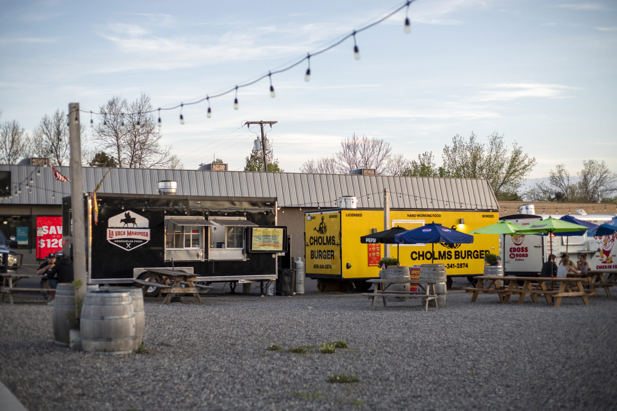 Food trucks and picnic tables under string lights at a Bozeman food park